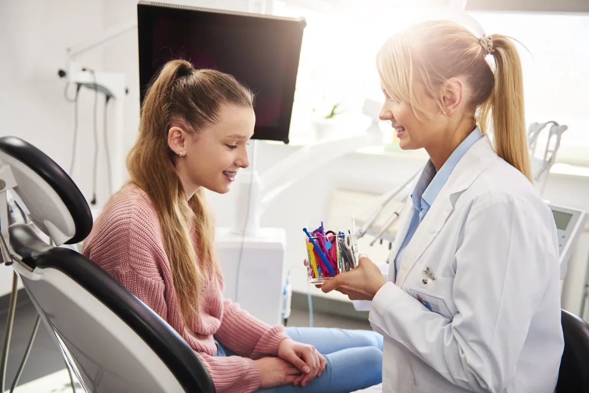 Ortodontist ve genç hasta diş teli lastiklerinin rengini seçiyor